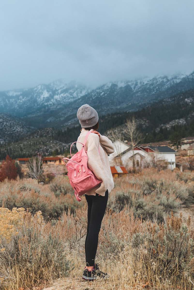 people woman with pink backpack standing near grass overlooking mountains person