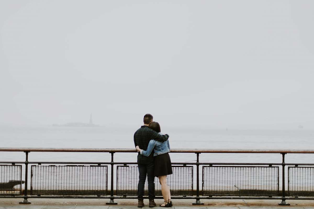 human couple standing in front of fence near body of water person
