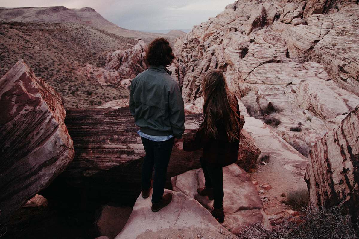 canyon man and woman standing on hill in front of hills during daytime human