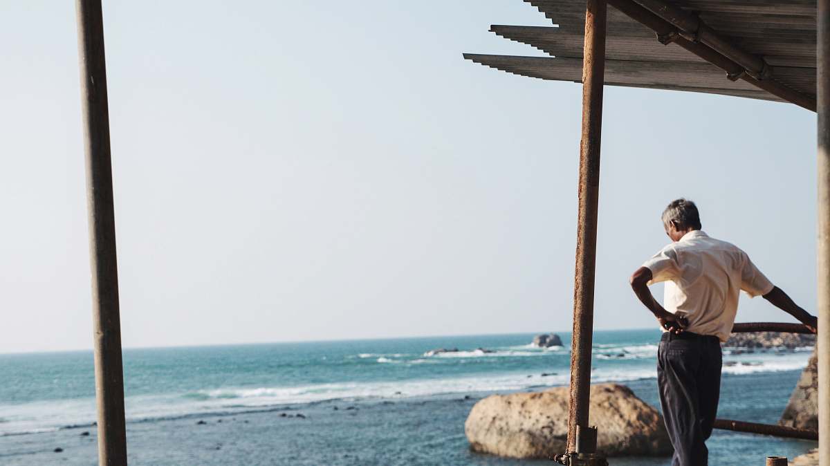 Capture the tranquility of a man leaning thoughtfully against a fence, gazing over the serene expanse of the ocean. This evocative scene takes place on a charming wooden porch, where the soothing sounds of the waves create a perfect backdrop for contemplation. Ideal for projects related to relaxation, travel, or coastal living, this image embodies a moment of peace and introspection, perfect for websites, blogs, and promotional material about nature, mindfulness, or seaside excursions.