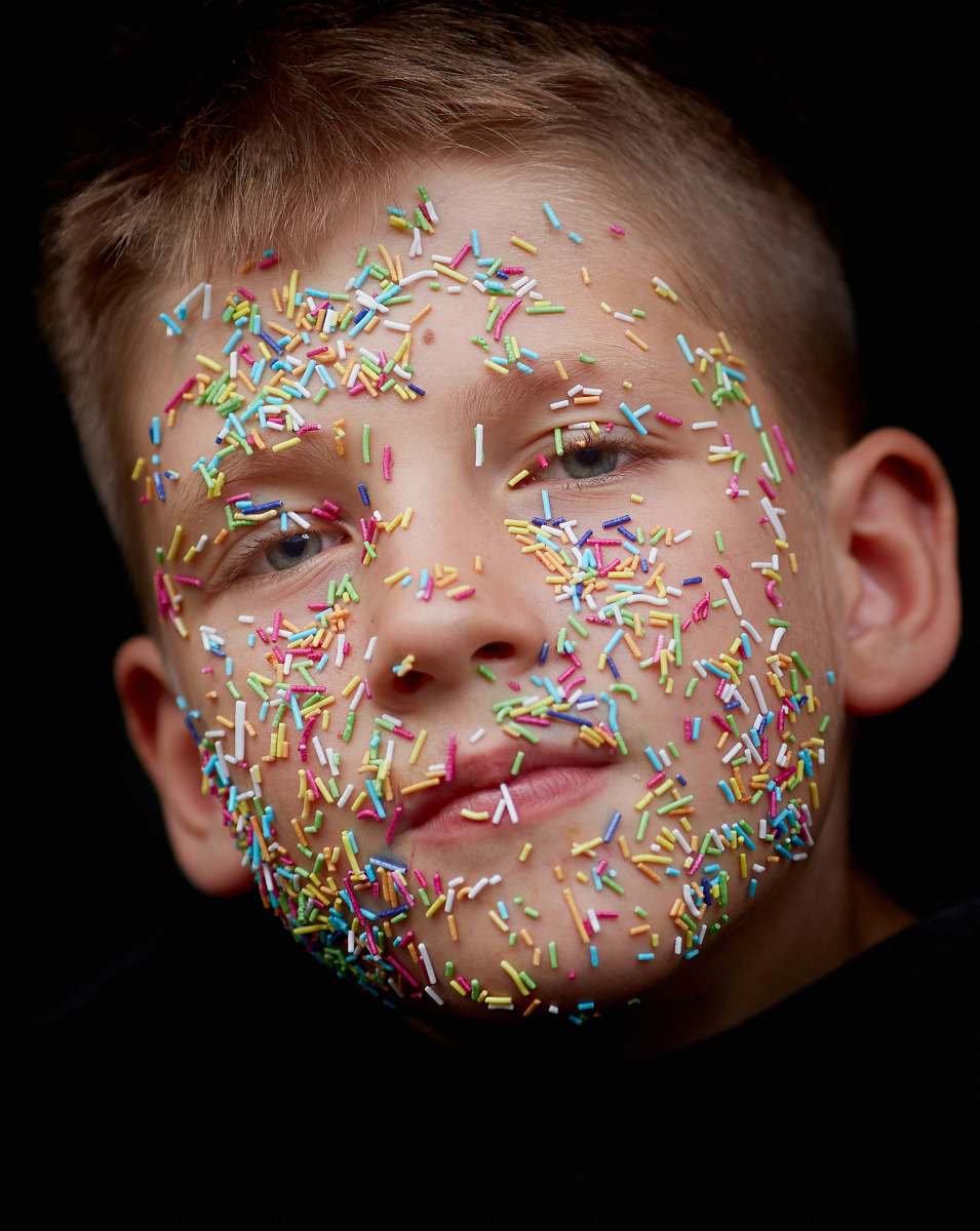 human assorted-color sprinkler candies on boy's face person
