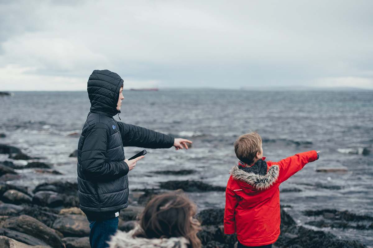 person boy and man pointing on sea taken under white clouds during daytime human