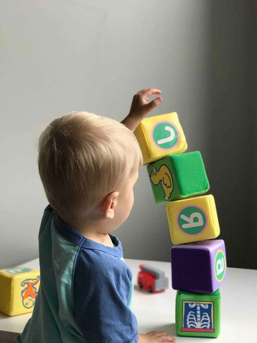 human boy playing cube on white wooden table person