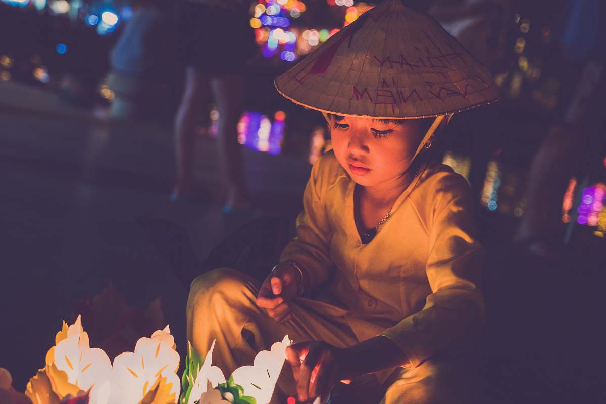 human boy wearing brown cap lighting candles during nightime person