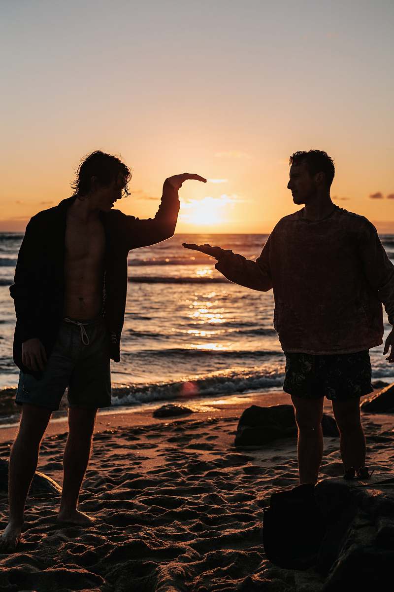 human close-up photo of two men shaking hands near beach at sunset person