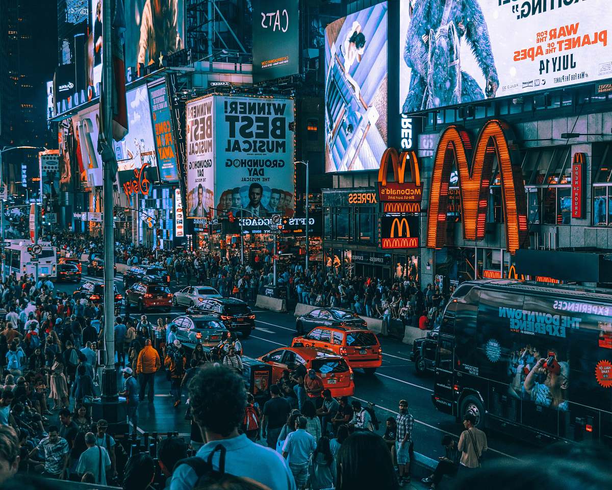 human crowd of people waking on street in front of McDonald's building person