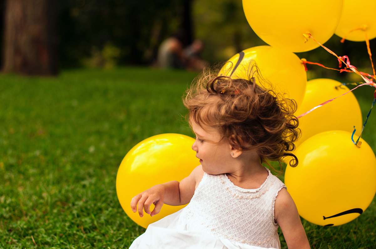 human girl sitting on grass near balloon person