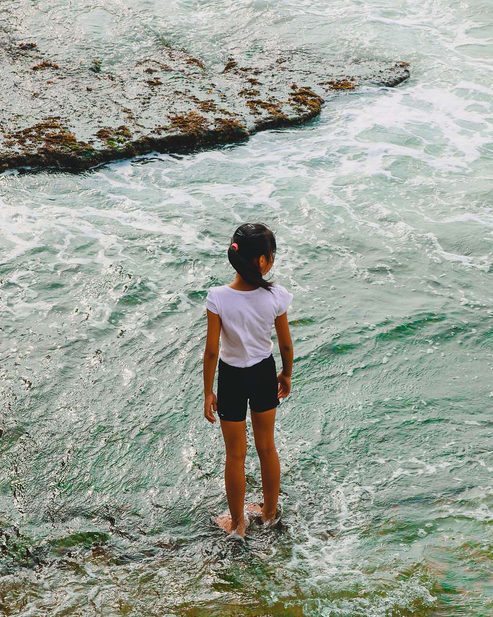 person girl standing on the rock and body of water human