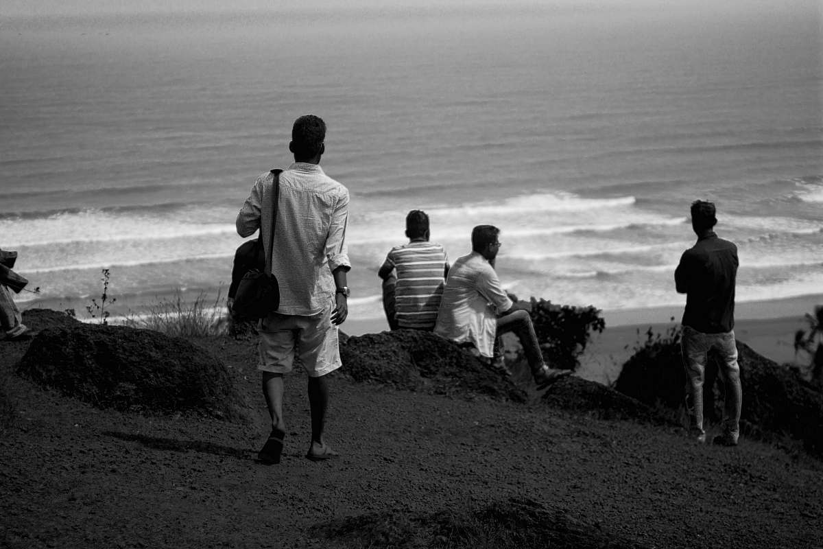 human grayscale photo of person walking and facing the seashore black-and-white