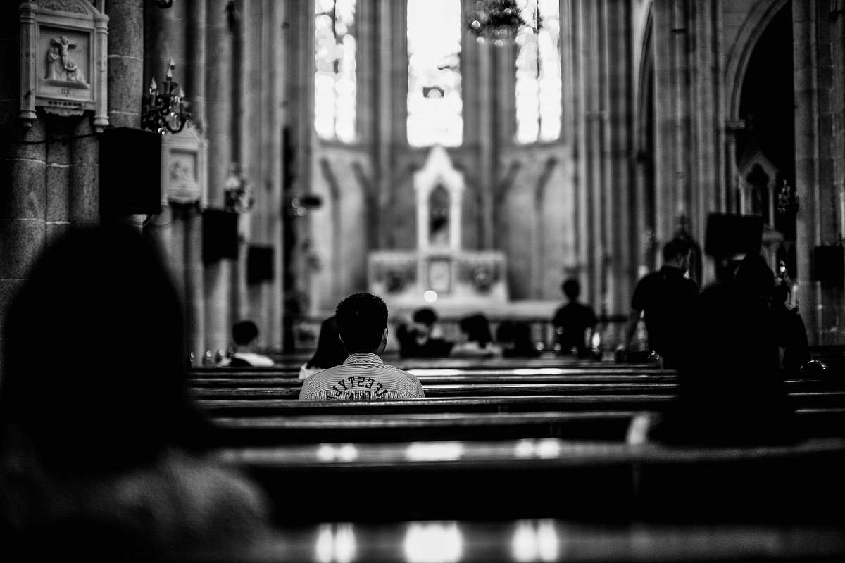 person grayscale photo of wooden pew black-and-white