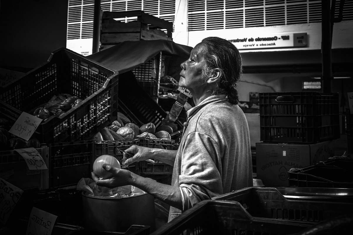 human grayscale photography of woman holding round fruit near crates black-and-white