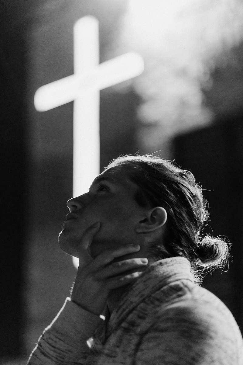 human grayscale photography of woman standing near white cross signage black-and-white