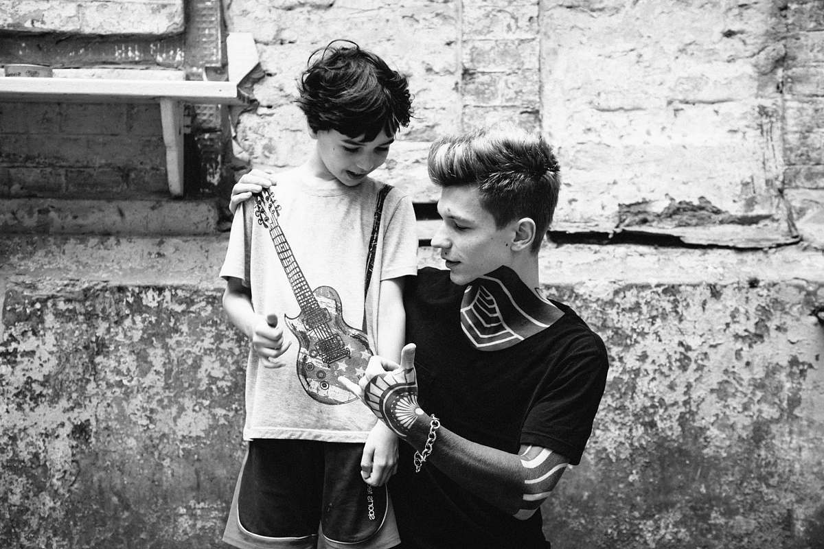 human man and boy looking on guitar in grayscale photo black-and-white