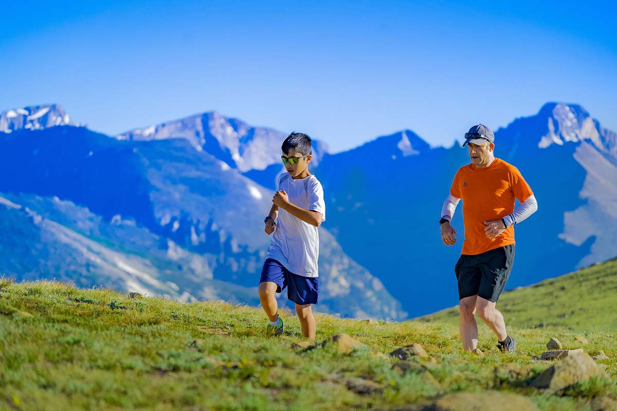 human man and boy running on green grass field at daytime person