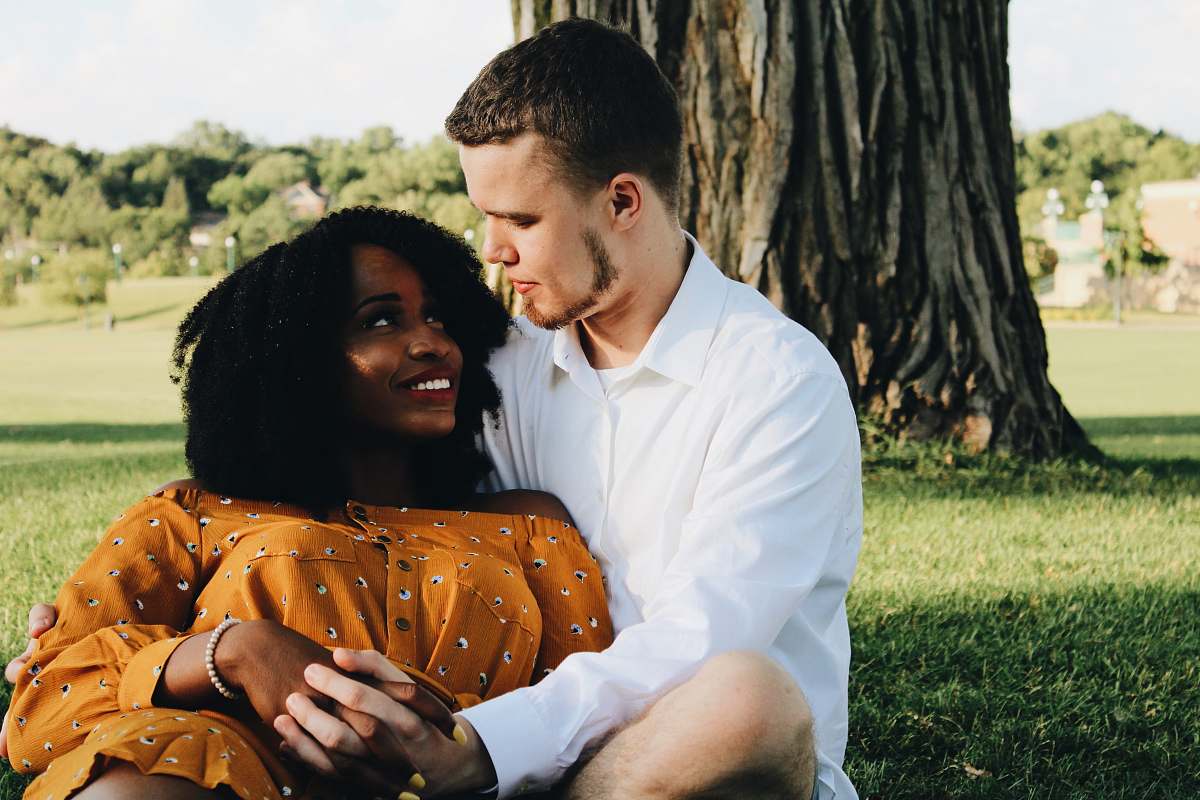 person man and woman hugging while sitting on lawn grass human