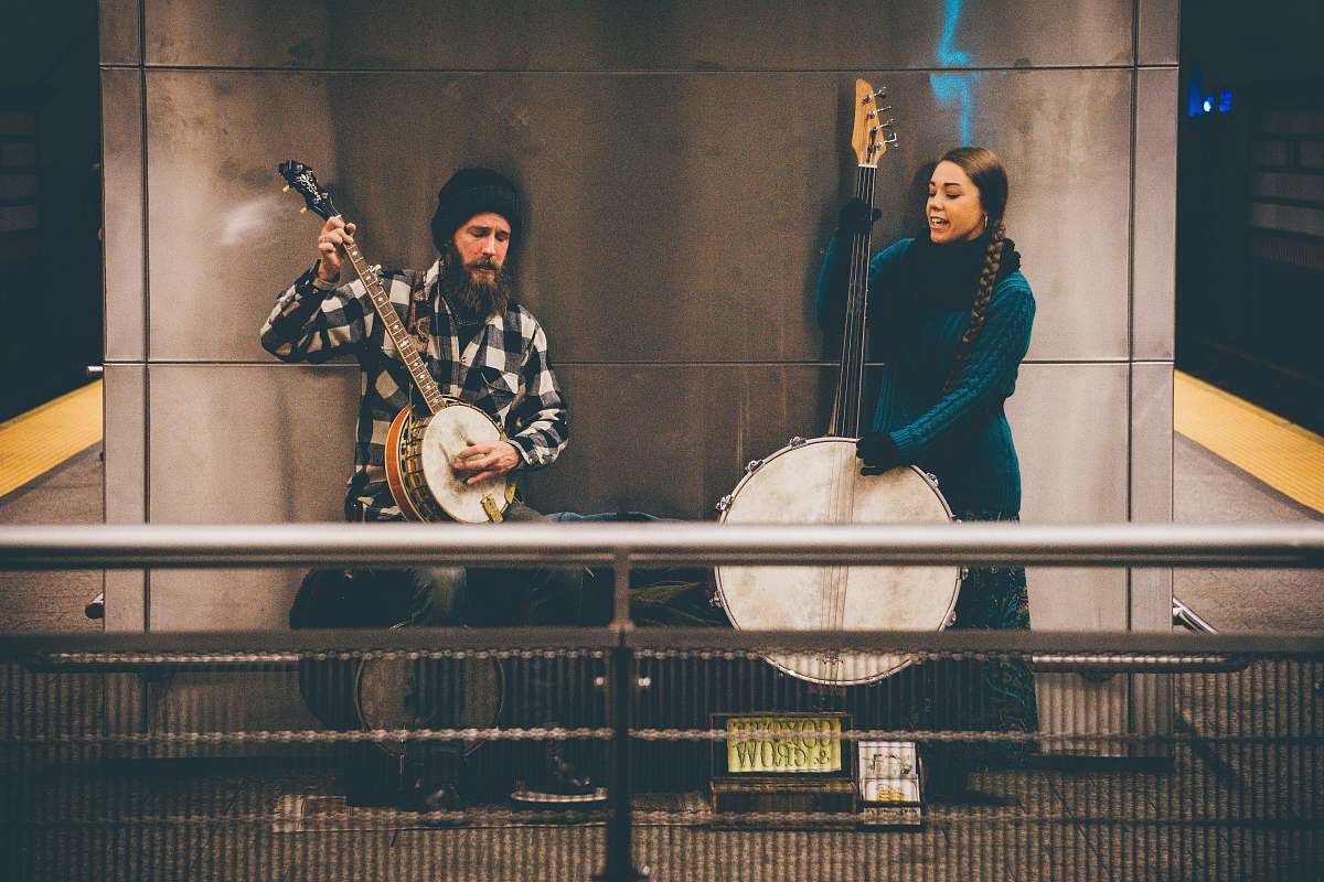 human man and woman playing string instruments standing near wall person