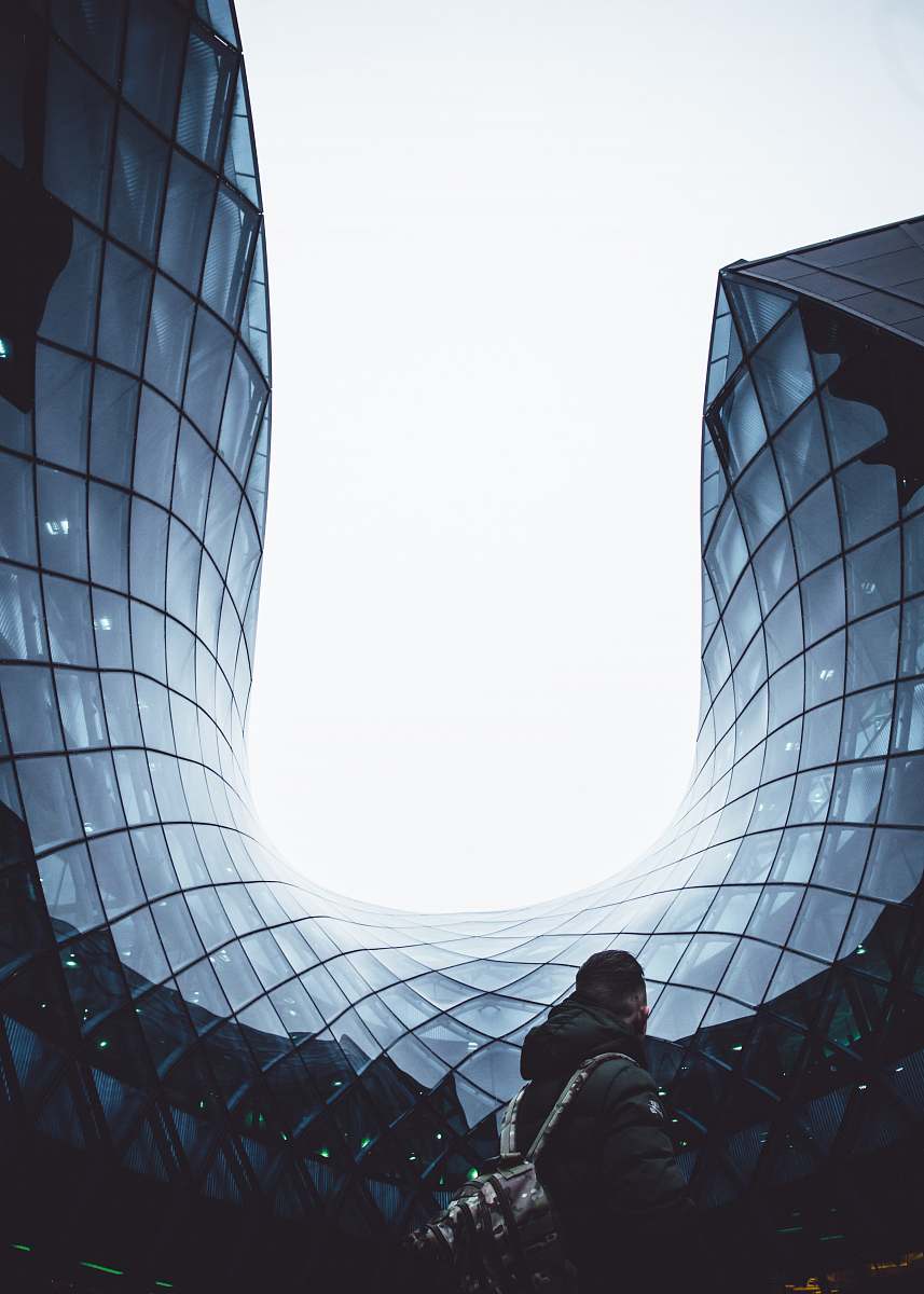 person man carrying backpack white standing in front of glass building human