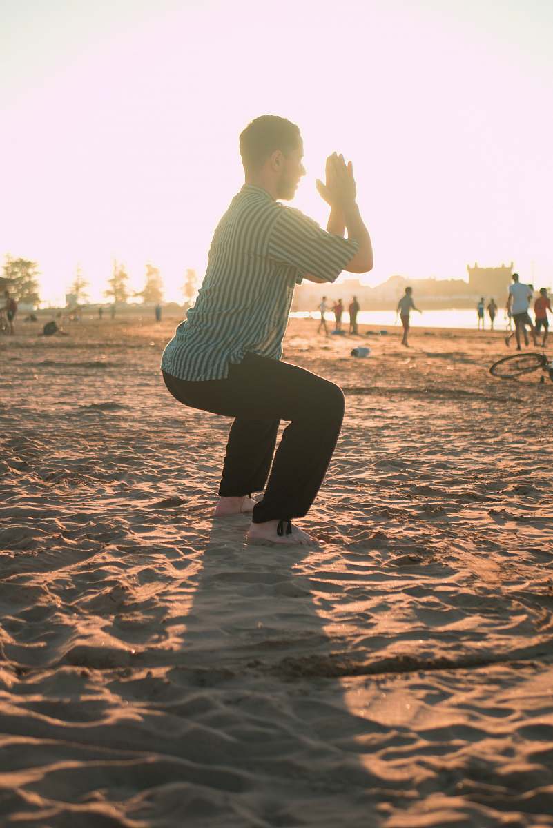 human man closing his hands white squatting on sand person