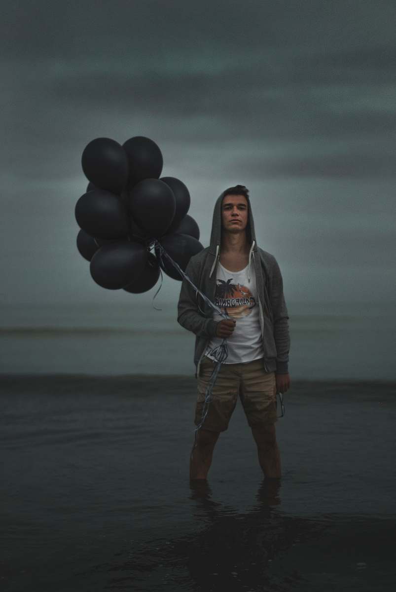 human man holding balloons while on water person