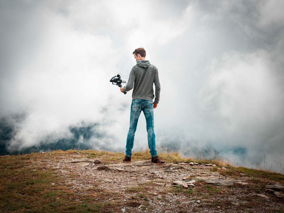 human man holding camera with stabilizer while standing person