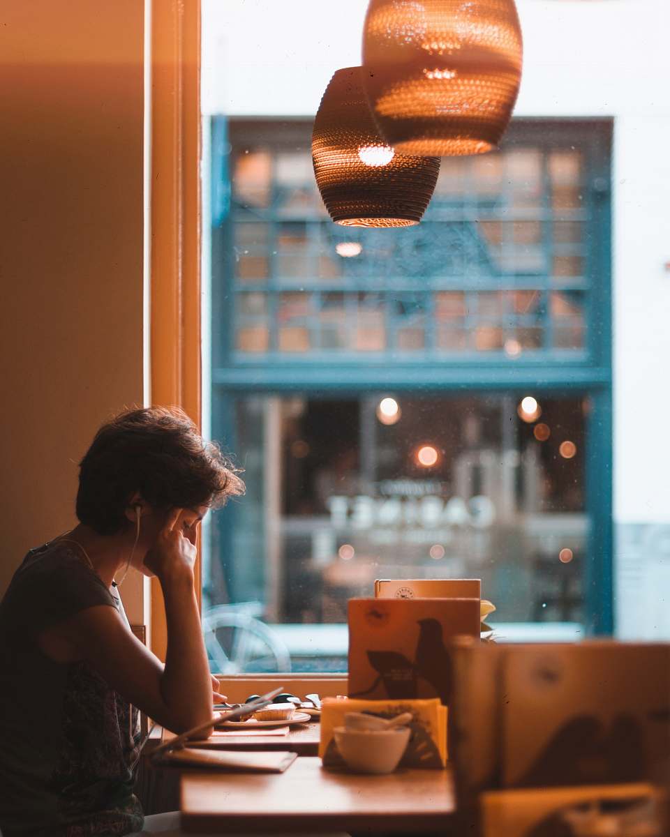 human man holding on tablet while sitting on chair in restaurant person