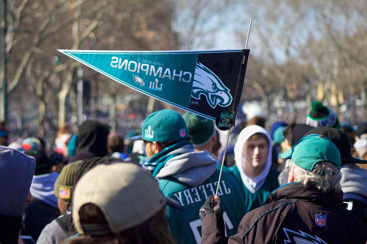person man holding Philadelphia Eagle pennant crowd