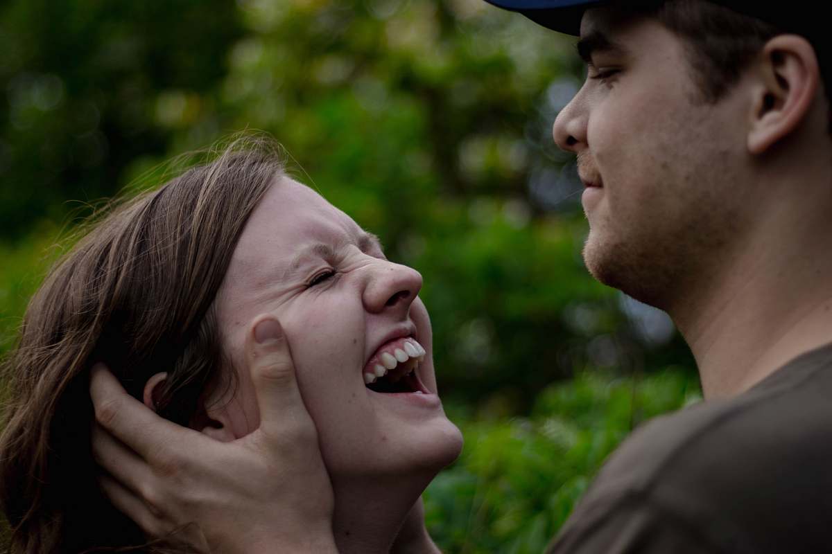 person man holding the face of woman smiling near plants at daytime human