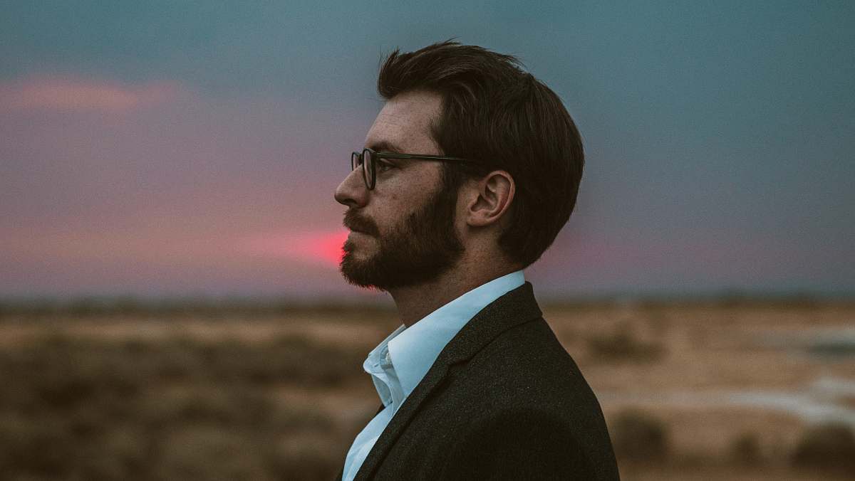 human man in black formal suit wearing eyeglasses person