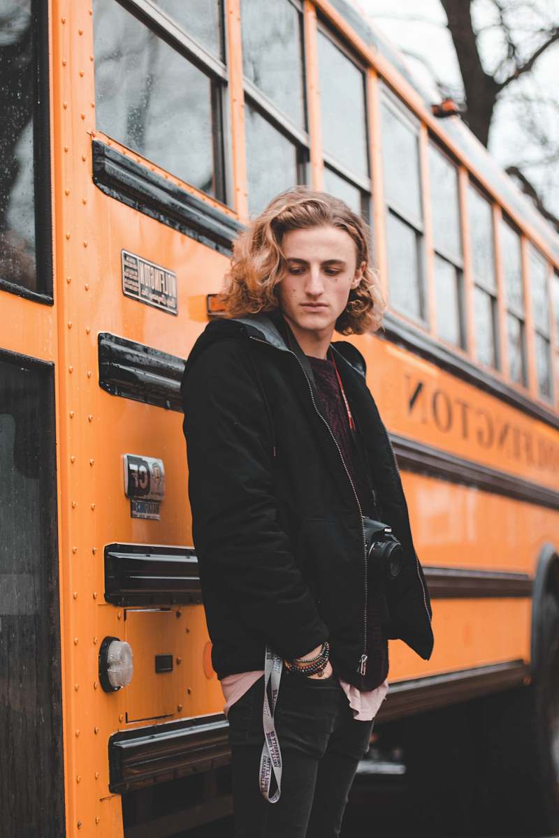person man in black zip-up jacket standing beside bus human