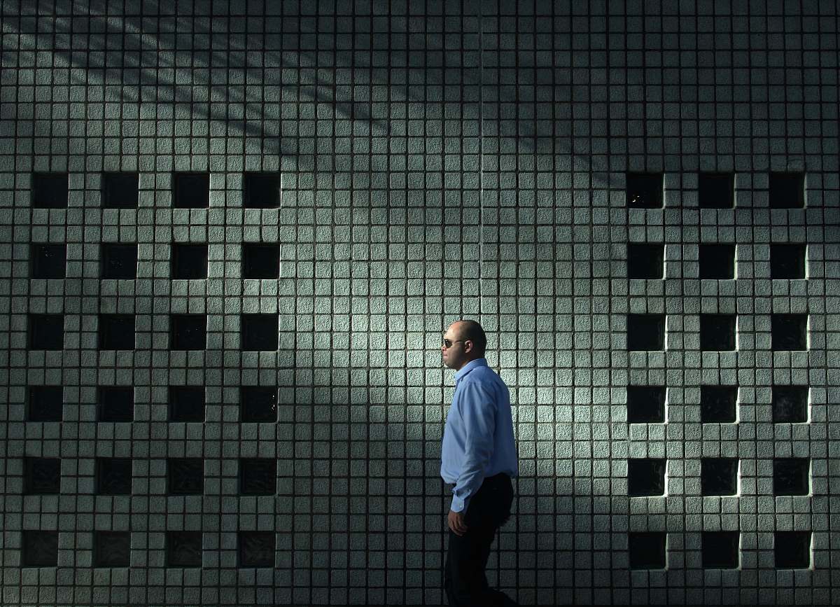 human man in blue dress shirt walking near gray concrete wall person