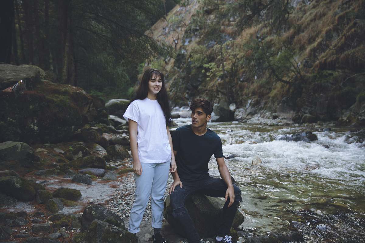 person man in blue shirt sitting beside woman in white shirt standing on river human