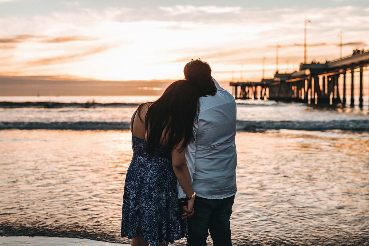 human man in dress shirt beside woman in dress pier