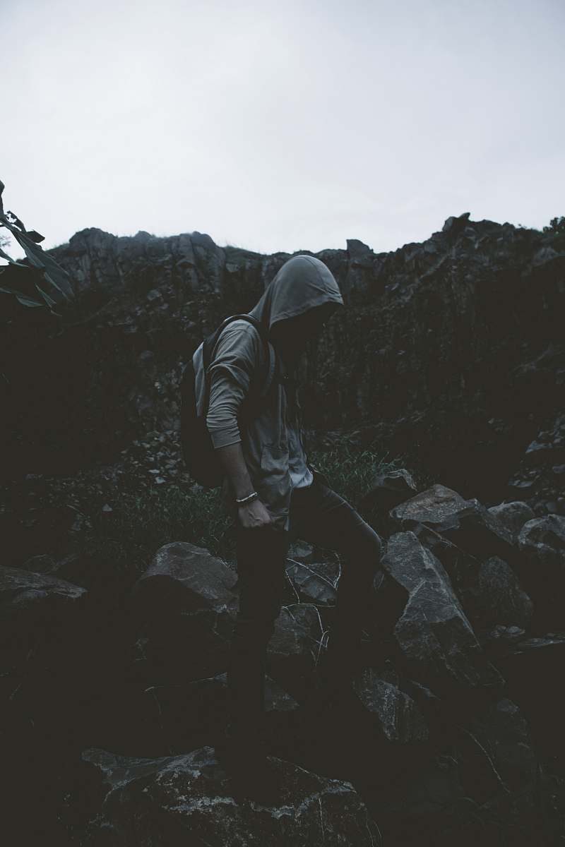 human man in hoodie stepping on rocks person