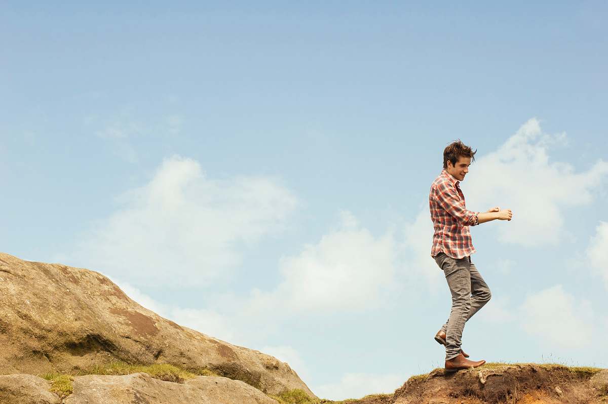 man man in red plaid top standing on hilltop during daytime male