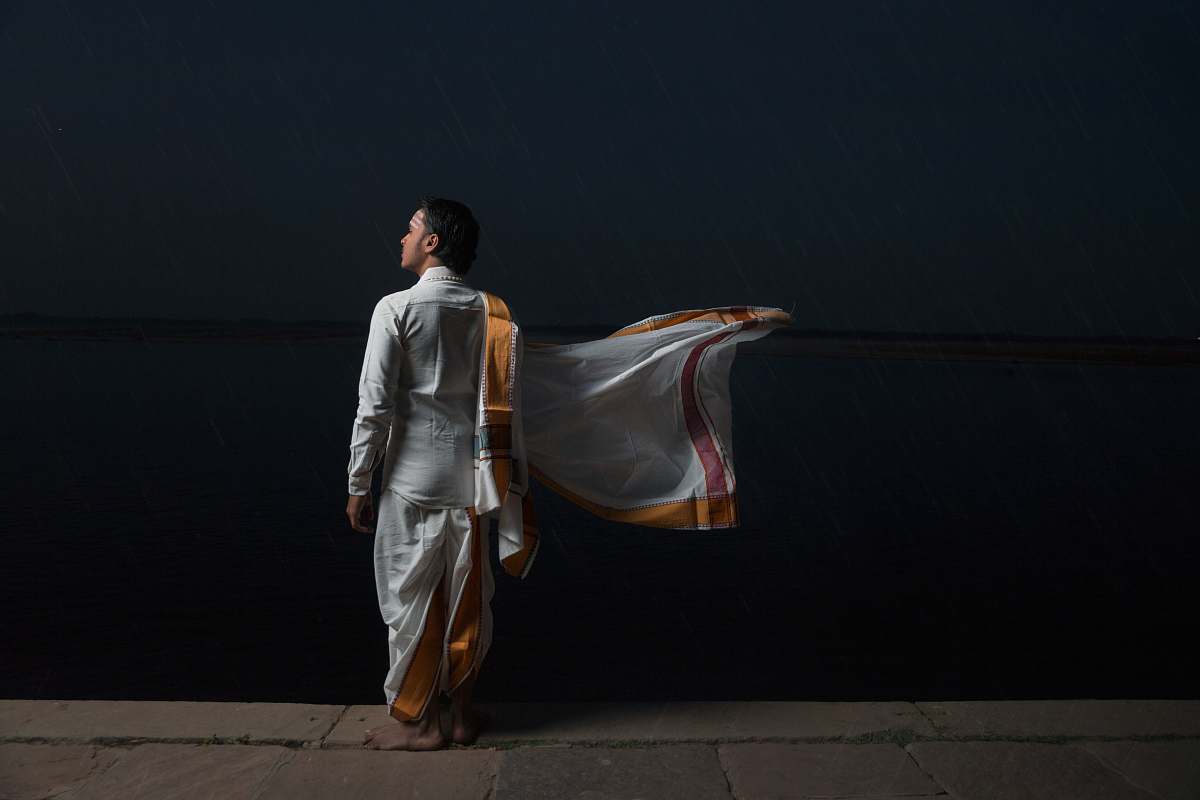 person man in white and brown traditional dress standing beside black wall human