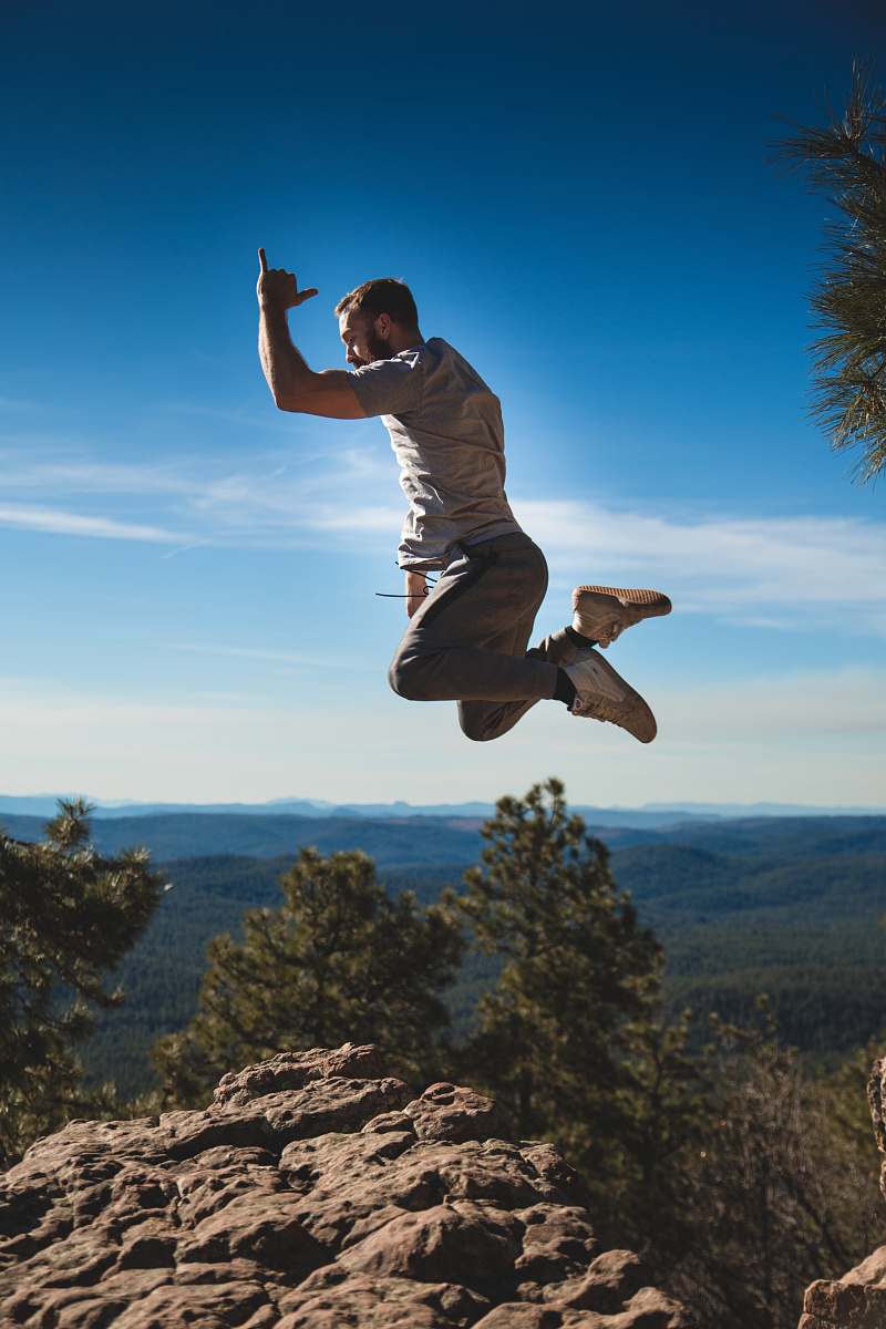 human man jumping on brown rock formation person