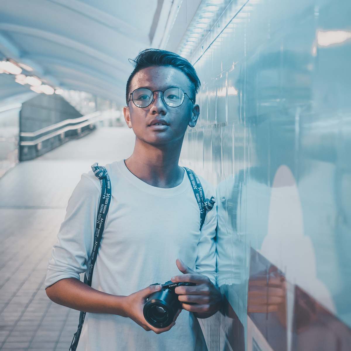 human man leaning against wall while holding camera person