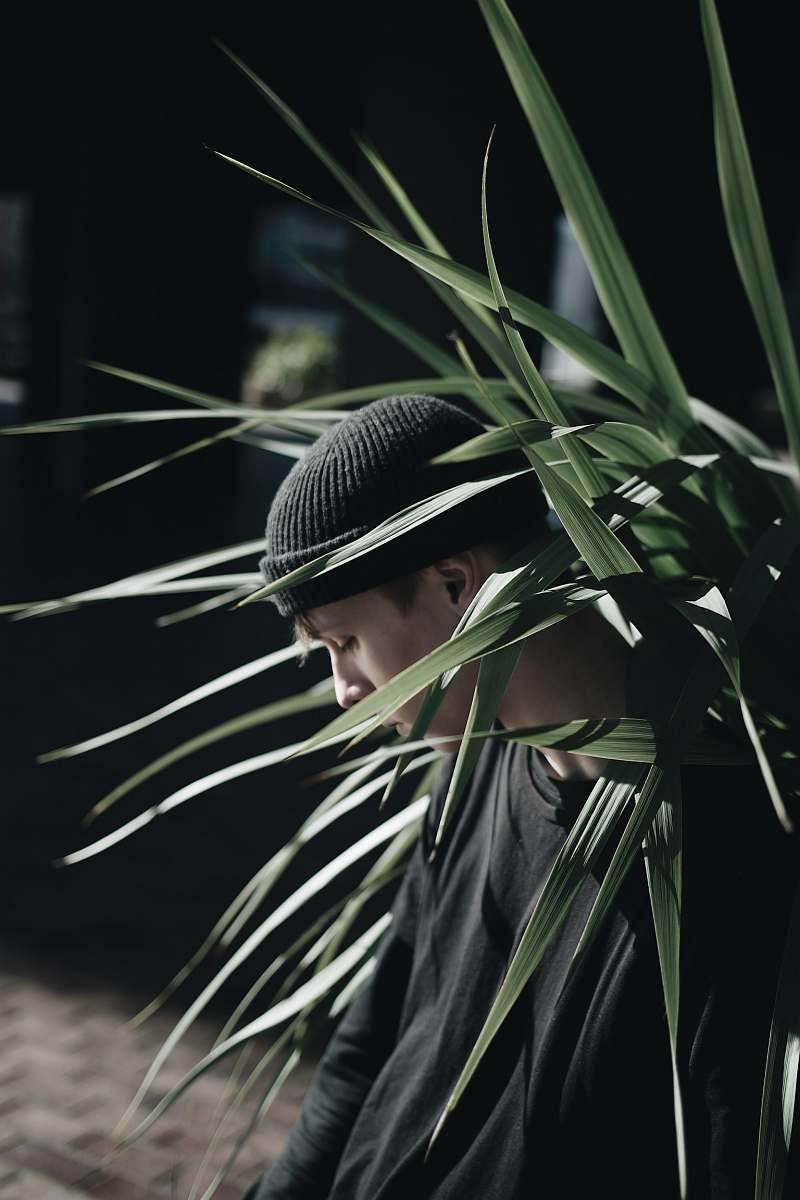 human man leaning on green leafed plant person