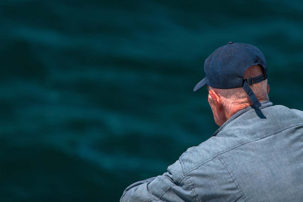 human man looking on body of water wearing black cap person