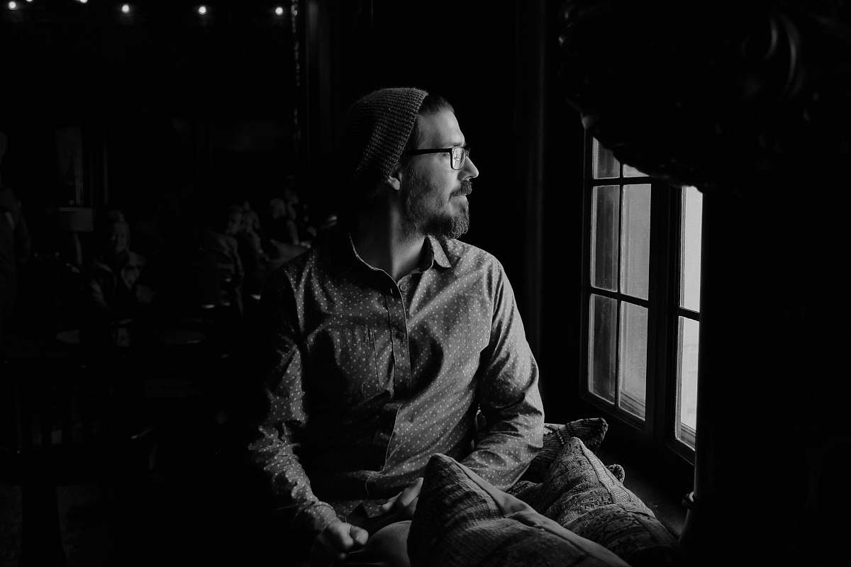 person man looking through glass window black-and-white