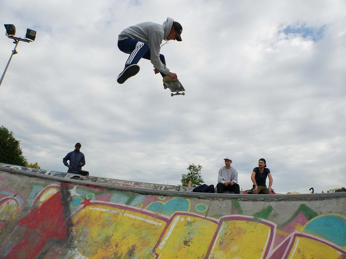 human man on air playing skateboard above skateboard ramp at daytime person