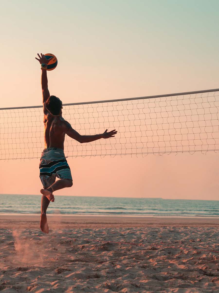 human man playing beach volleyball during daytime person