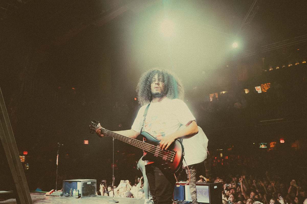 person man playing brown guitar perform on stage with crowd behind during nighttime human