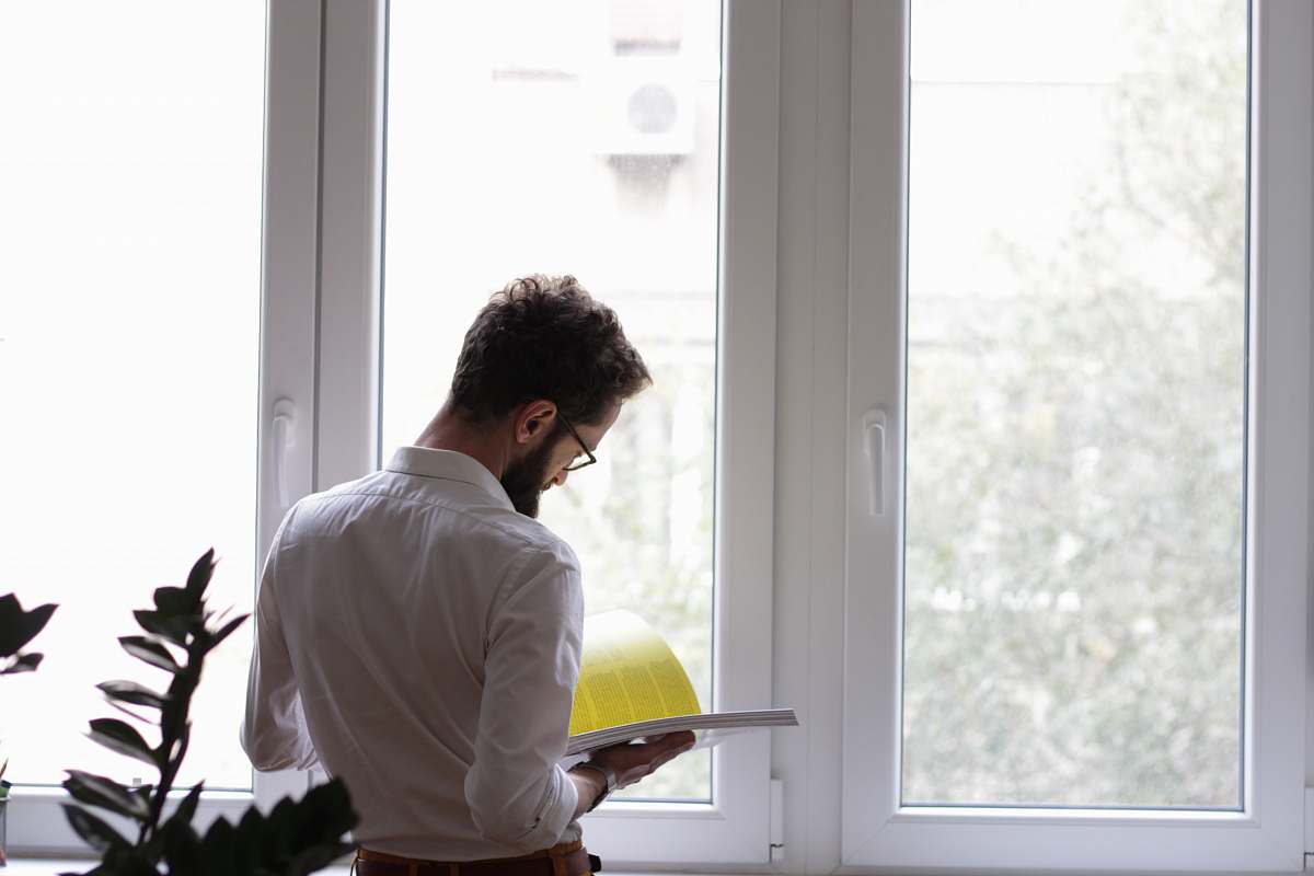 human man reading book in front of window person