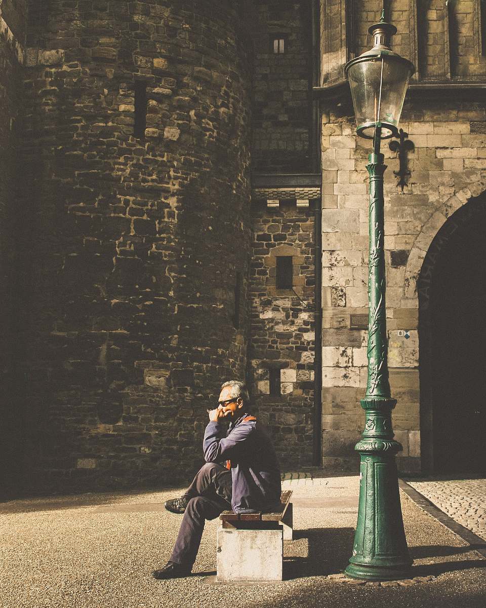 person man sitting on bench beside post lamp human