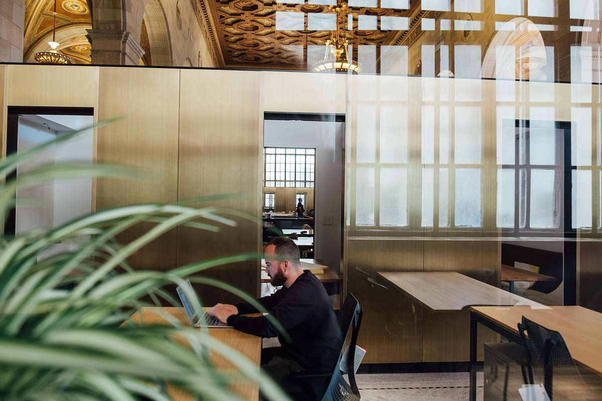 human man sitting on chair white using laptop beside door person