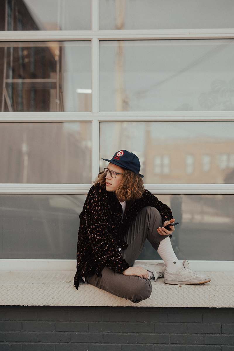 person man sitting on metal surface looking at his left human