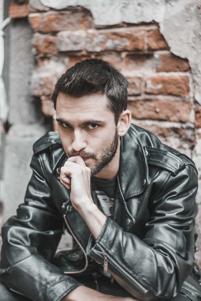 human man sitting while biting his right middle finger person