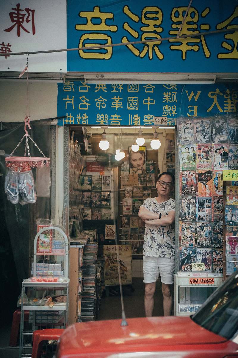 human man standing beside assorted-title DVD case lot person