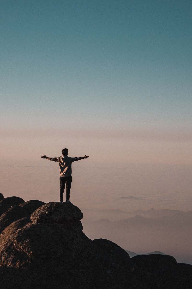 human man standing beside cliff person